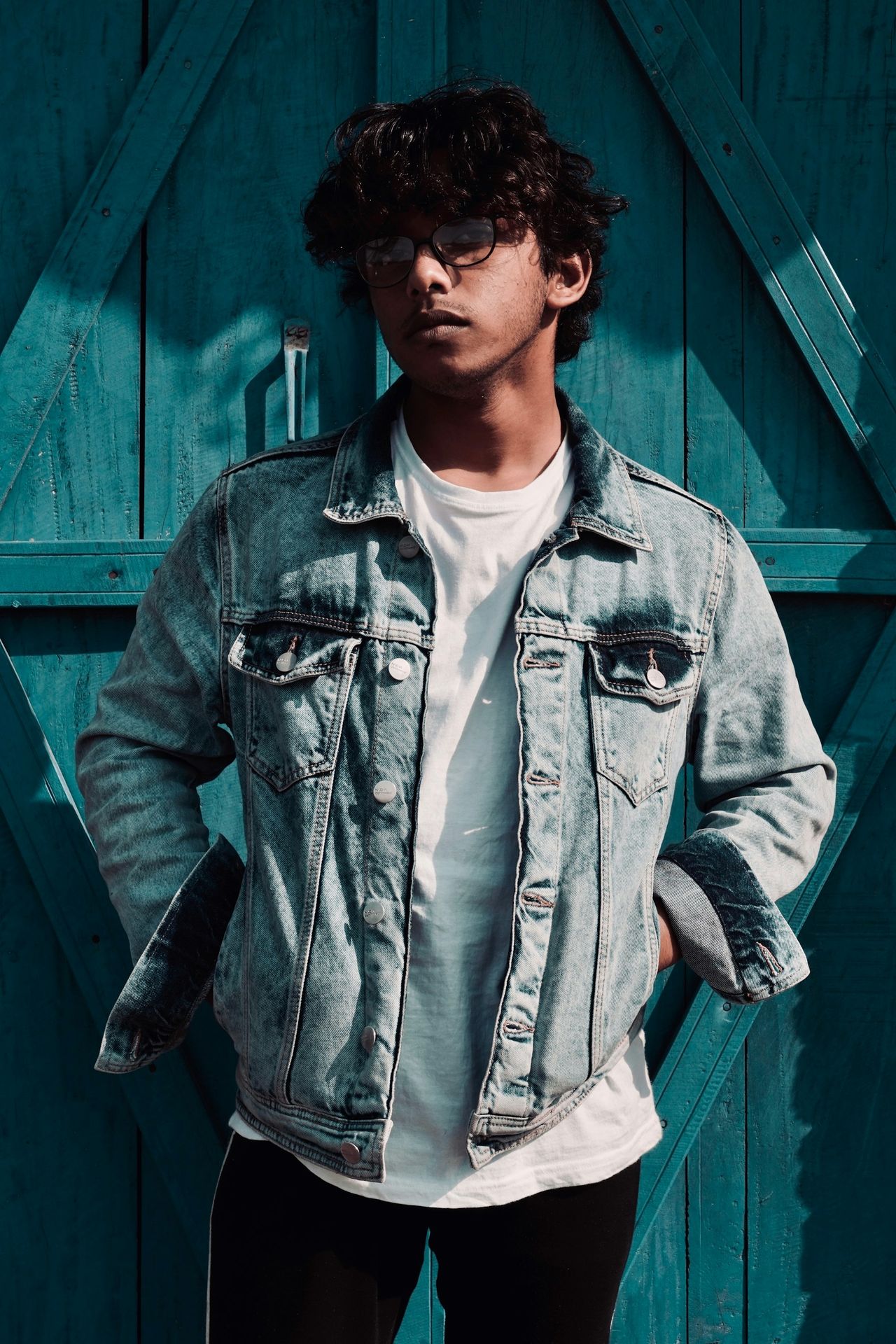 man standing beside blue wooden wall
